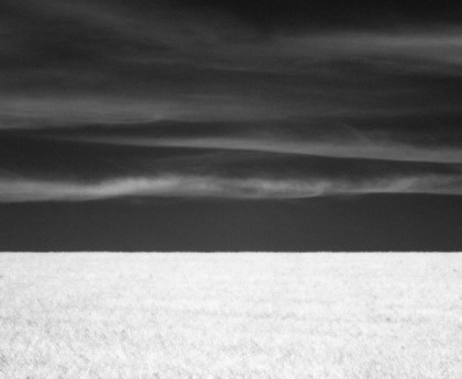 Clouds and dark sky over grassy field